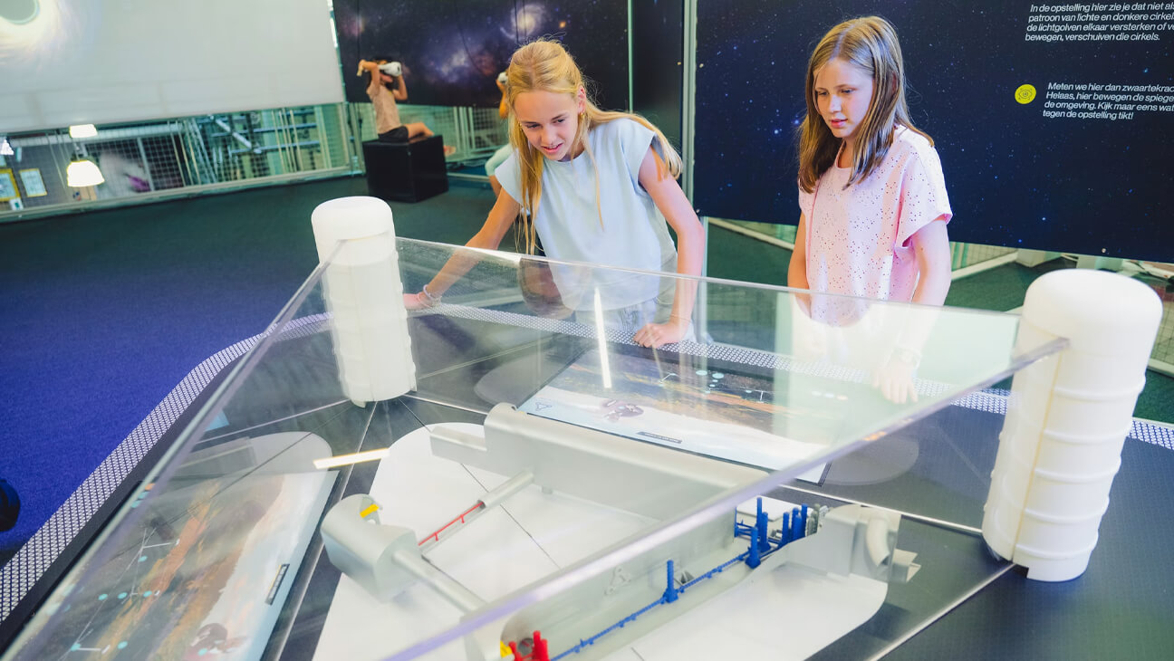 Kinderen op de expo 'einsteintelescoop' kijken naar een maquette van de telescoop