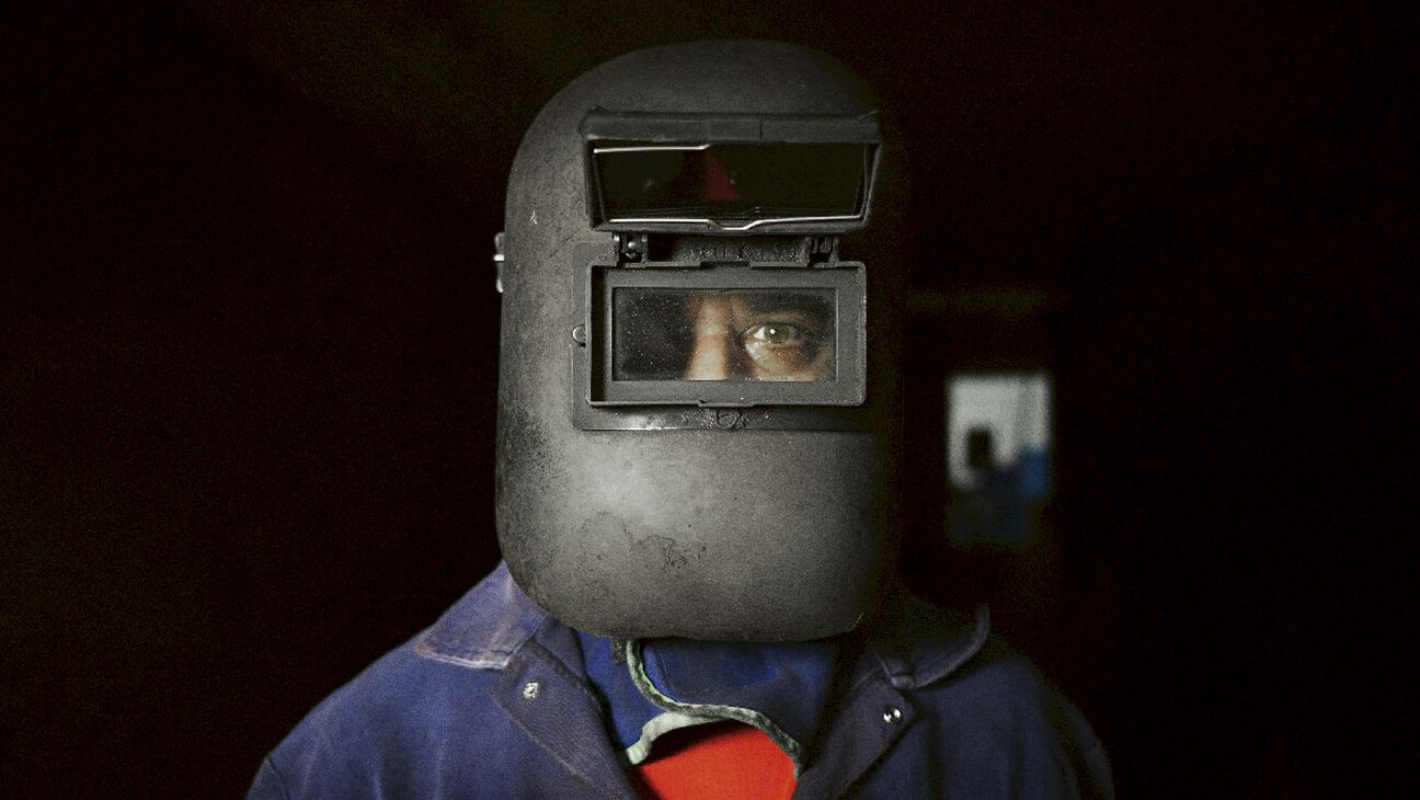 Man met een lasmasker kijkt in de lens