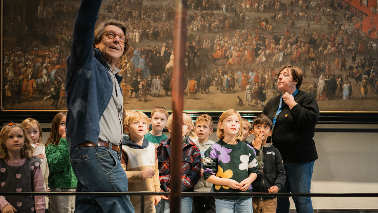 Gids toont iets op een oud schilderij aan een groep kinderen