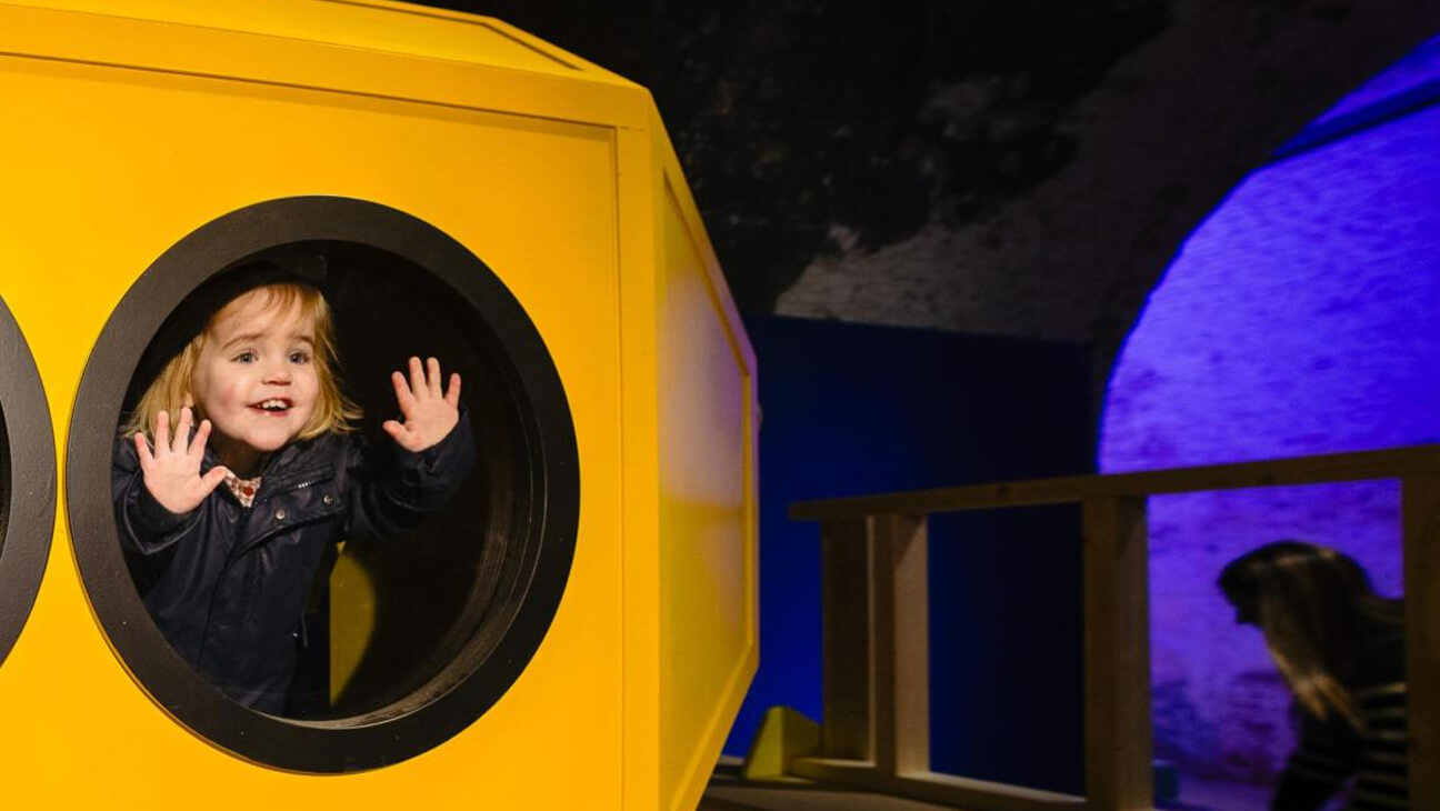 Kind kijkt door een raam van een gele duikboot