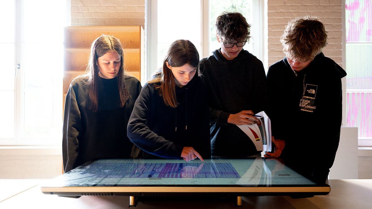 4 leerlingen kijken naar een groot scherm