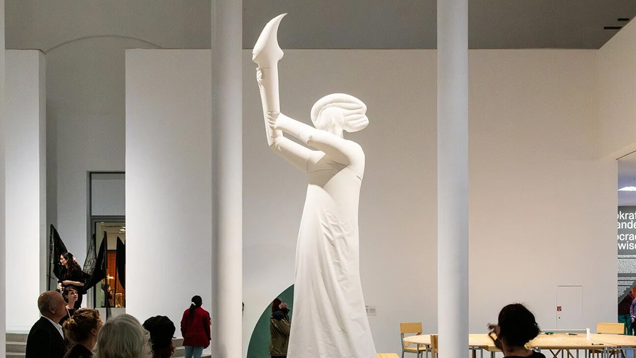 Groot wit beeld van een vrouw die een toorts vasthoud in een zaal van het designmuseum Gent