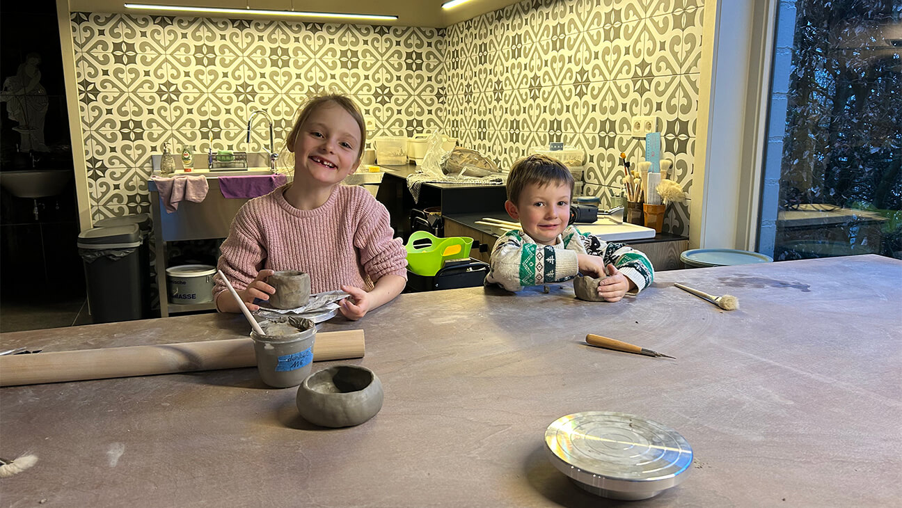 2 kinderen in een keuken die werken met keramiek