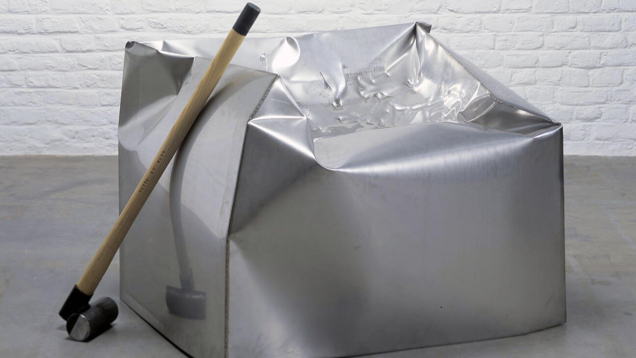 Hamer bij een grote metalen kubus