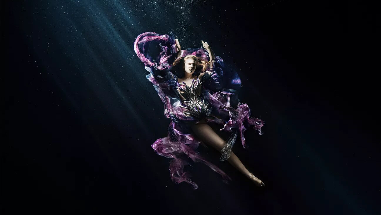 Kunstwerk van Iris Van Herpen. Een vrouw in kleurrijke kleren onder water